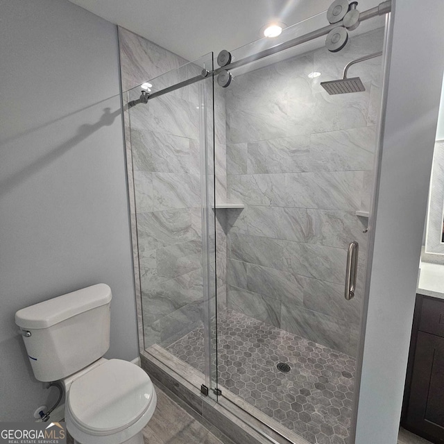 bathroom with a shower stall, toilet, and vanity