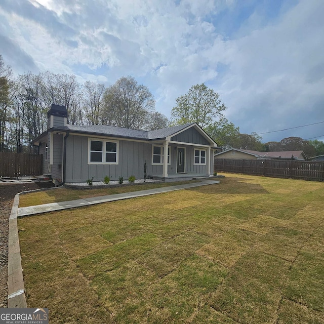 ranch-style home with board and batten siding, a front lawn, a chimney, and fence