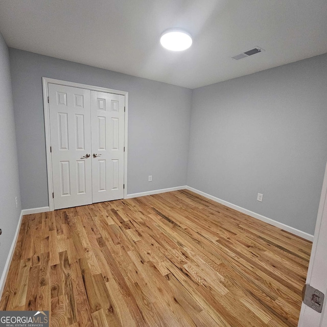 unfurnished bedroom featuring baseboards, visible vents, light wood-style floors, and a closet