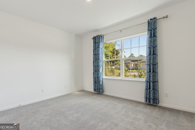unfurnished room with carpet flooring and baseboards