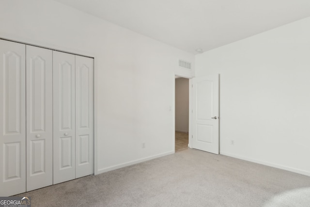 unfurnished bedroom with carpet floors, a closet, visible vents, and baseboards