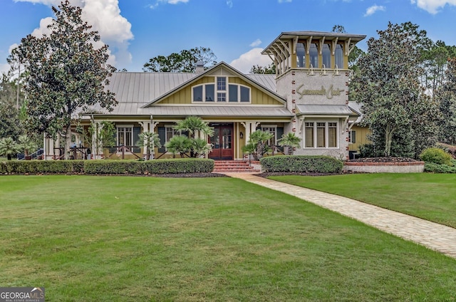 view of front of home with board and batten siding, covered porch, a front yard, and metal roof