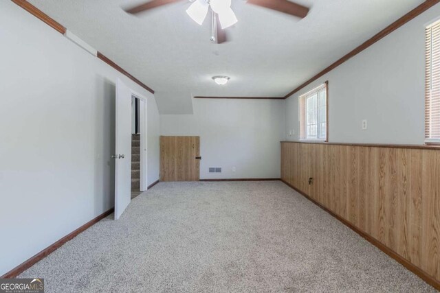 2092 Countydown Ln, Stone Mountain, GA 30088 - unfurnished room featuring wooden walls, visible vents, a ceiling fan, ornamental molding, and light colored carpet