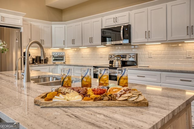 1016 Twisted Oak Rd Unit 115, Talking Rock, GA 30175 - kitchen with stainless steel appliances, tasteful backsplash, white cabinetry, and light stone countertops