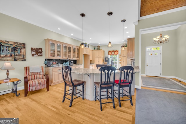 kitchen with a breakfast bar area, glass insert cabinets, light wood finished floors, a notable chandelier, and light stone countertops
