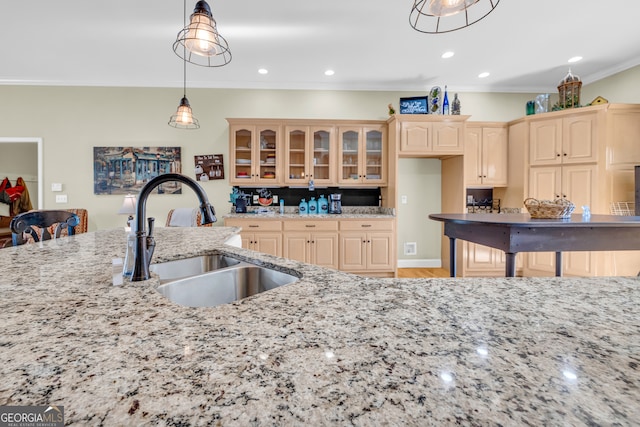 kitchen featuring a sink, recessed lighting, glass insert cabinets, light stone countertops, and ornamental molding