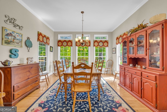 dining space with an inviting chandelier, crown molding, light wood-style floors, and baseboards