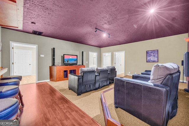 home theater room featuring visible vents, baseboards, wood finished floors, and a textured ceiling