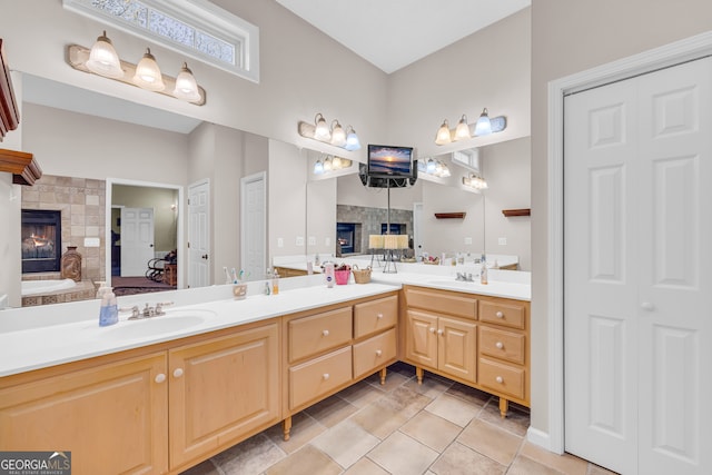 full bathroom with a bath, a lit fireplace, a sink, and double vanity