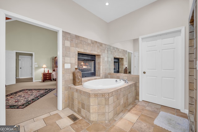 bathroom with a bath, a tiled fireplace, and recessed lighting