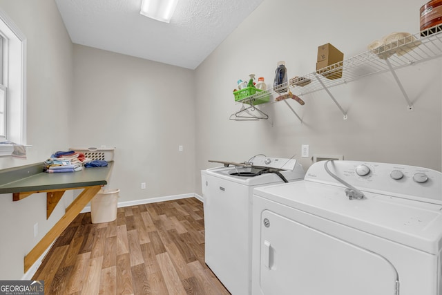 laundry area with a textured ceiling, separate washer and dryer, light wood-style floors, baseboards, and laundry area