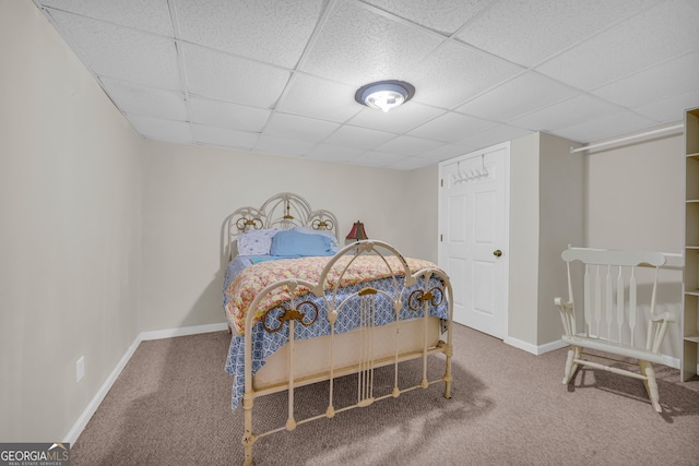 carpeted bedroom with a paneled ceiling and baseboards