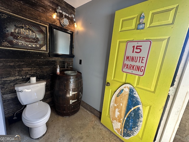 bathroom with concrete flooring, vanity, toilet, and baseboards