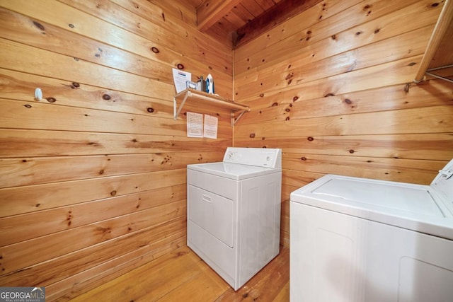 washroom with washing machine and clothes dryer, wooden walls, and laundry area