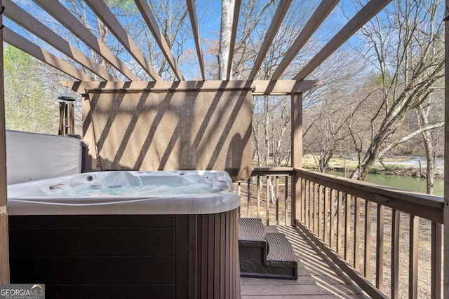 wooden terrace featuring a hot tub and a water view