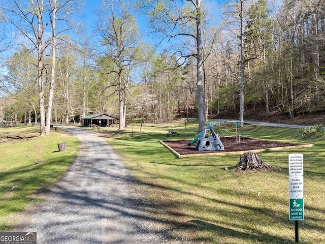 view of home's community with playground community, driveway, and a yard