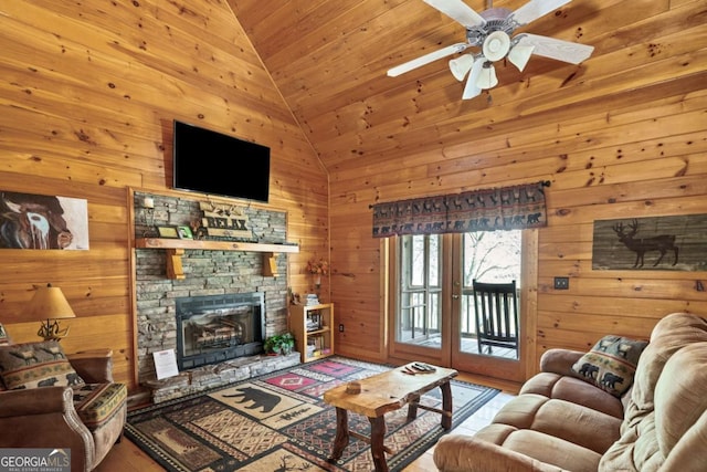 living room featuring vaulted ceiling, a ceiling fan, wooden walls, a fireplace, and wooden ceiling