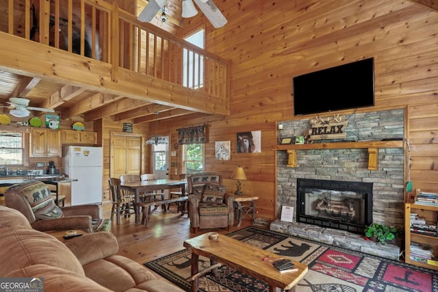 living room featuring a ceiling fan, a healthy amount of sunlight, and wooden walls