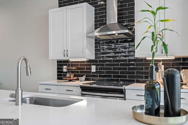 kitchen with tasteful backsplash, wall chimney range hood, stainless steel range with electric stovetop, and a sink