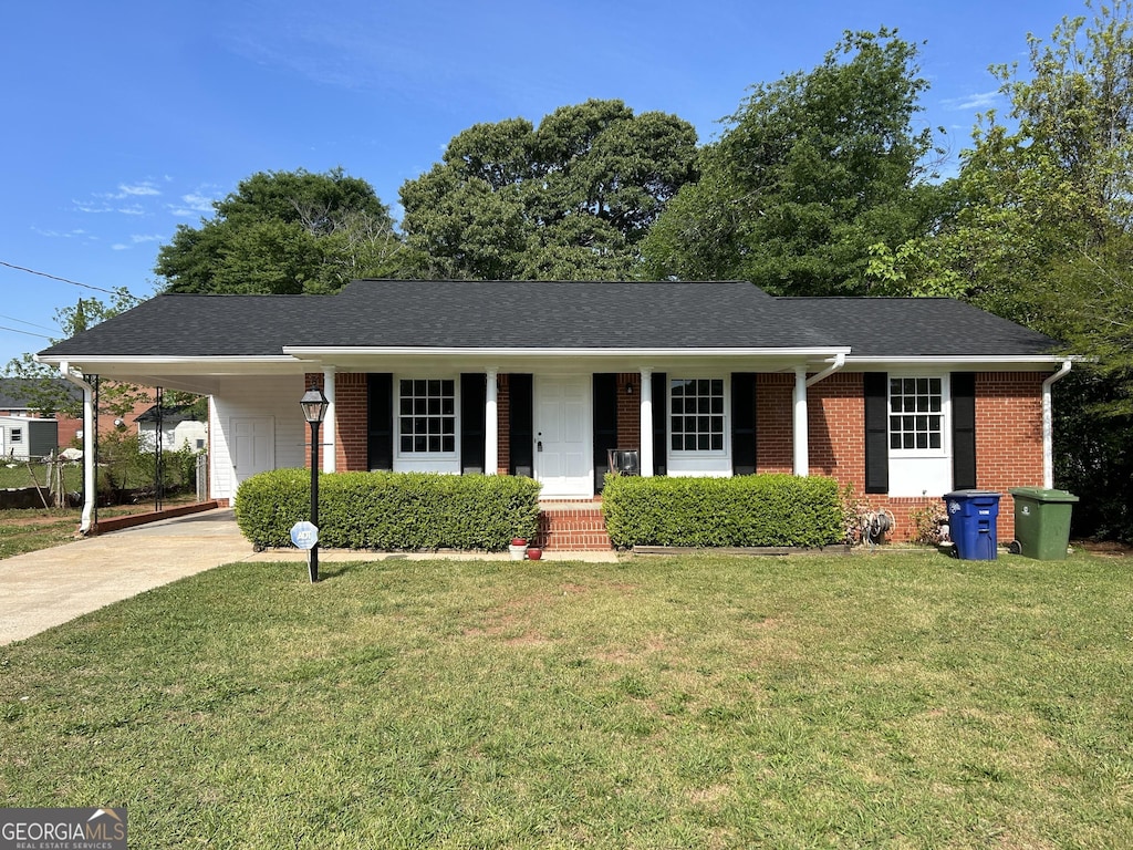 ranch-style home with a carport, driveway, a porch, brick siding, and a front yard