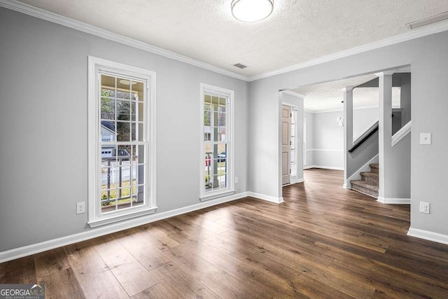 spare room featuring a textured ceiling, dark wood-style flooring, visible vents, stairs, and crown molding