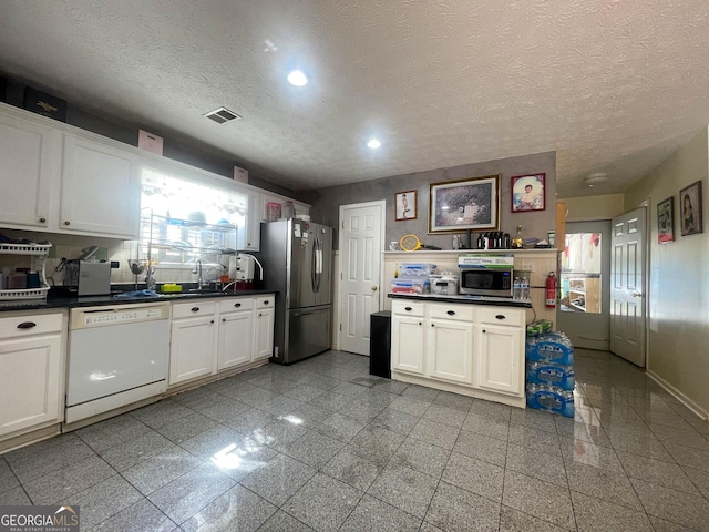 kitchen with dark countertops, visible vents, a wealth of natural light, and appliances with stainless steel finishes