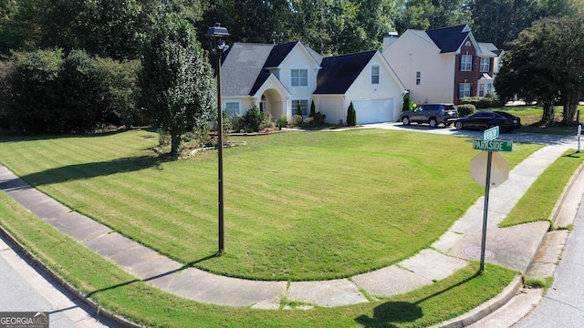 view of front of home with an attached garage, driveway, and a front lawn