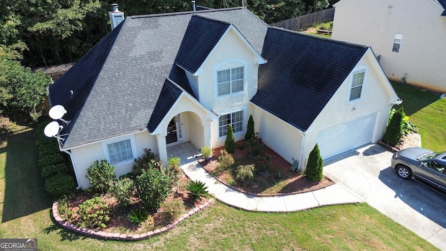 view of front facade featuring stucco siding, driveway, fence, and a shingled roof