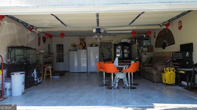 garage featuring freestanding refrigerator, refrigerator, and a garage door opener