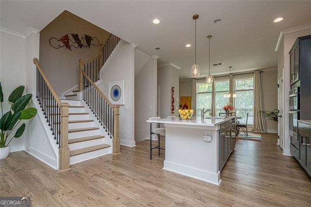 820 Fair View Cir, Roswell, GA 30076 - kitchen with light countertops, light wood-style floors, crown molding, baseboards, and a kitchen island with sink