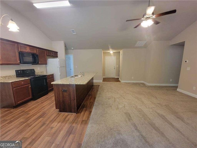 115 Heather Ln, Commerce, GA 30529 - kitchen with vaulted ceiling, a ceiling fan, black appliances, light wood-style floors, and a kitchen island with sink