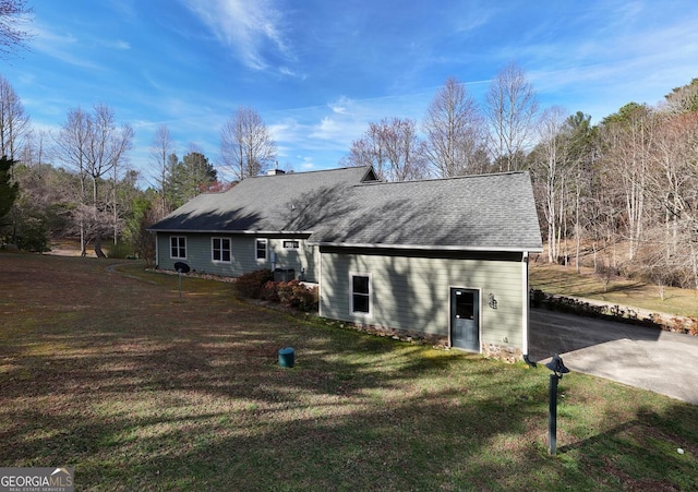 rear view of property with a lawn and roof with shingles