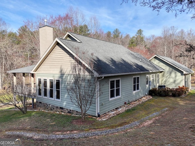 view of property exterior with a lawn, a chimney, and roof with shingles
