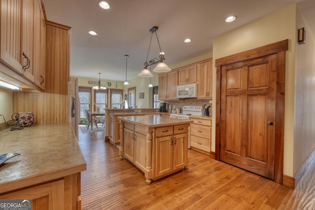 kitchen with light wood finished floors, an inviting chandelier, decorative backsplash, white appliances, and light countertops