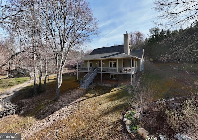 rear view of property featuring stairs, roof with shingles, a chimney, and covered porch