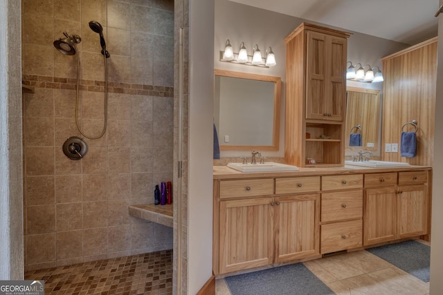 bathroom with tile patterned flooring, a sink, double vanity, and tiled shower