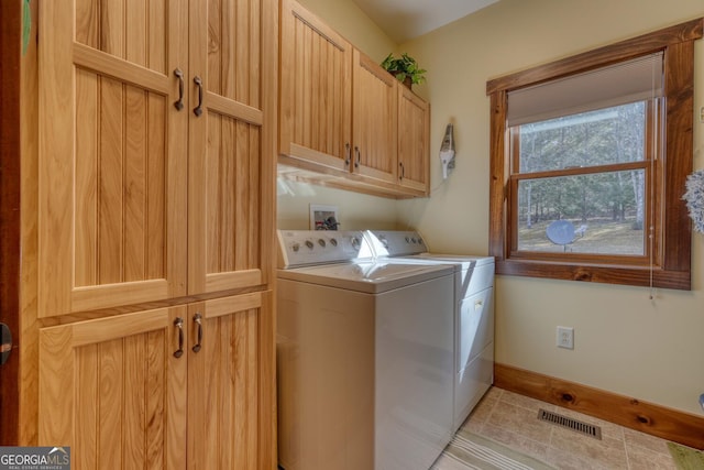 clothes washing area featuring washing machine and clothes dryer, light tile patterned flooring, cabinet space, baseboards, and visible vents