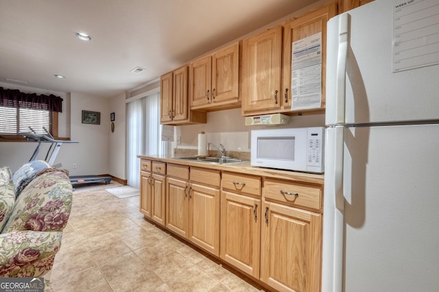 kitchen featuring light countertops, a wealth of natural light, a sink, and white appliances