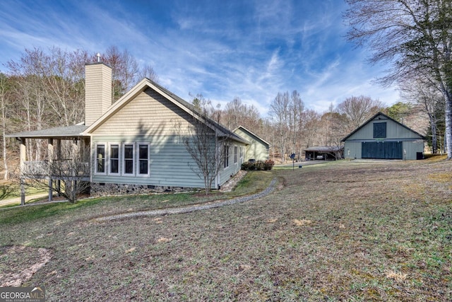 view of side of property with a chimney, an outdoor structure, crawl space, and a yard