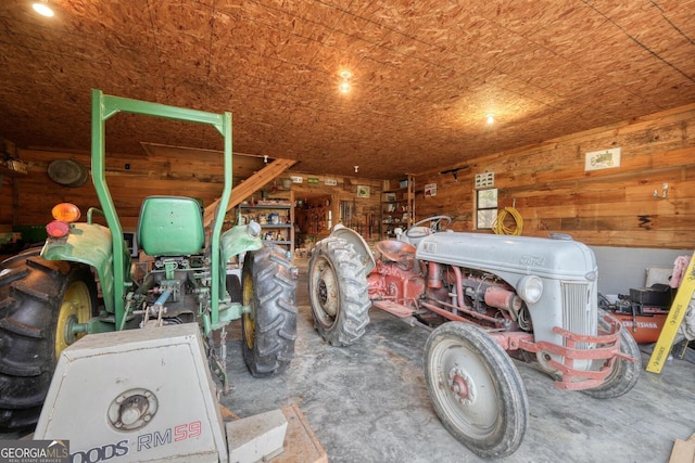 misc room with unfinished concrete flooring, wooden walls, and a garage