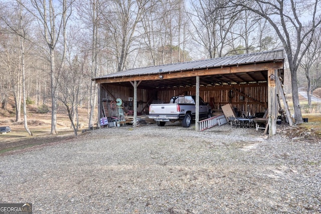view of parking featuring driveway, an outbuilding, and a carport