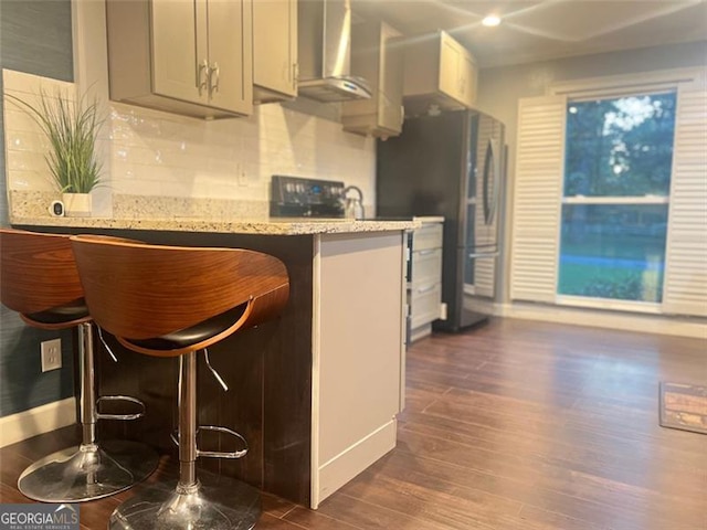 3629 Embry Cir, Atlanta, GA 30341 - kitchen featuring light stone counters, freestanding refrigerator, wall chimney exhaust hood, decorative backsplash, and dark wood-style flooring