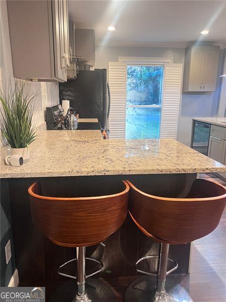 3629 Embry Cir, Atlanta, GA 30341 - kitchen with a breakfast bar, light stone counters, and gray cabinetry