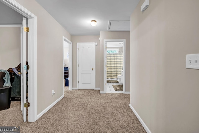 hall with carpet, baseboards, and attic access