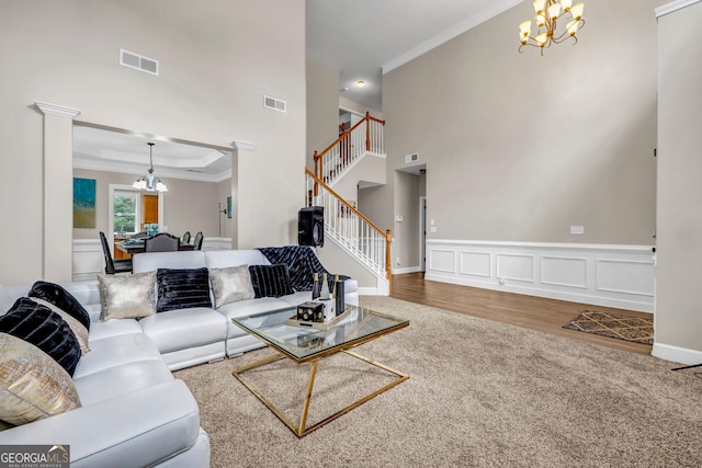 living room with a chandelier, crown molding, stairway, carpet, and a high ceiling