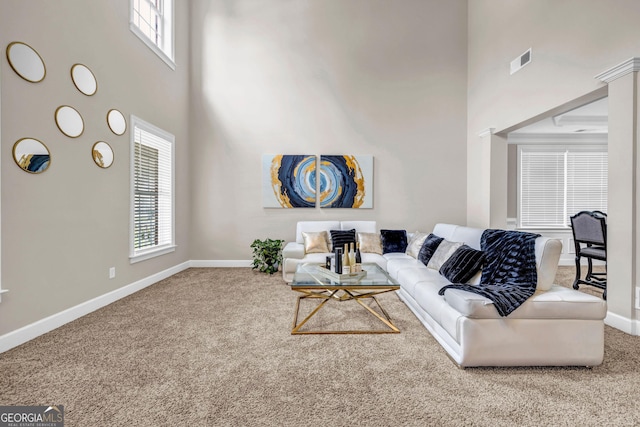 carpeted living room with a towering ceiling and baseboards
