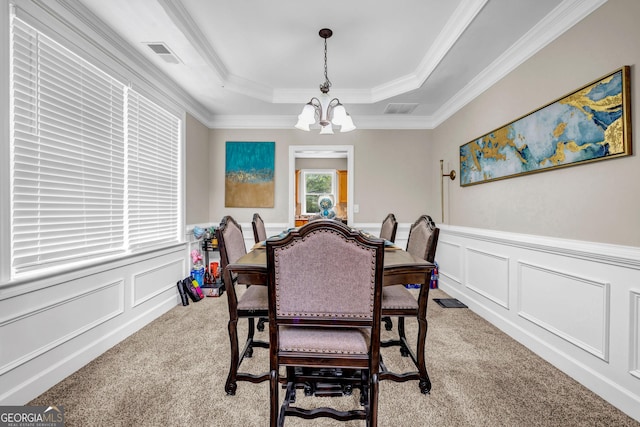 dining room featuring light colored carpet, a decorative wall, a raised ceiling, a chandelier, and a wainscoted wall
