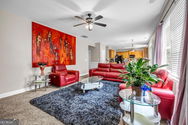 carpeted living room featuring a ceiling fan and baseboards