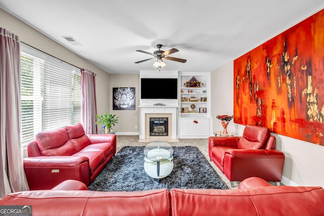 living room featuring carpet flooring, baseboards, a ceiling fan, built in features, and a fireplace with flush hearth