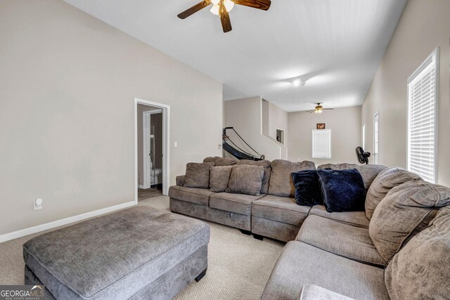 living room with a ceiling fan, light colored carpet, and baseboards
